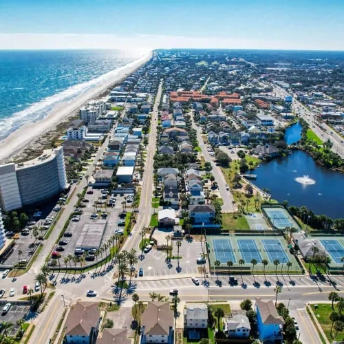 Aerial view of beachside neighborhoods with tennis courts, condos, and dense roadway access in a coastal corridor