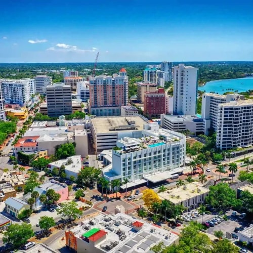 High-angle cityscape showcasing mid-rise and high-rise buildings near a bayfront with visible marina