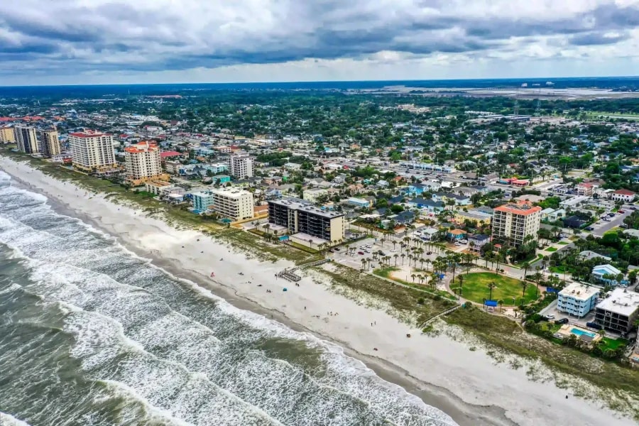 Drone capture of mid-rise coastal apartments lining a public beach in a densely built residential zone