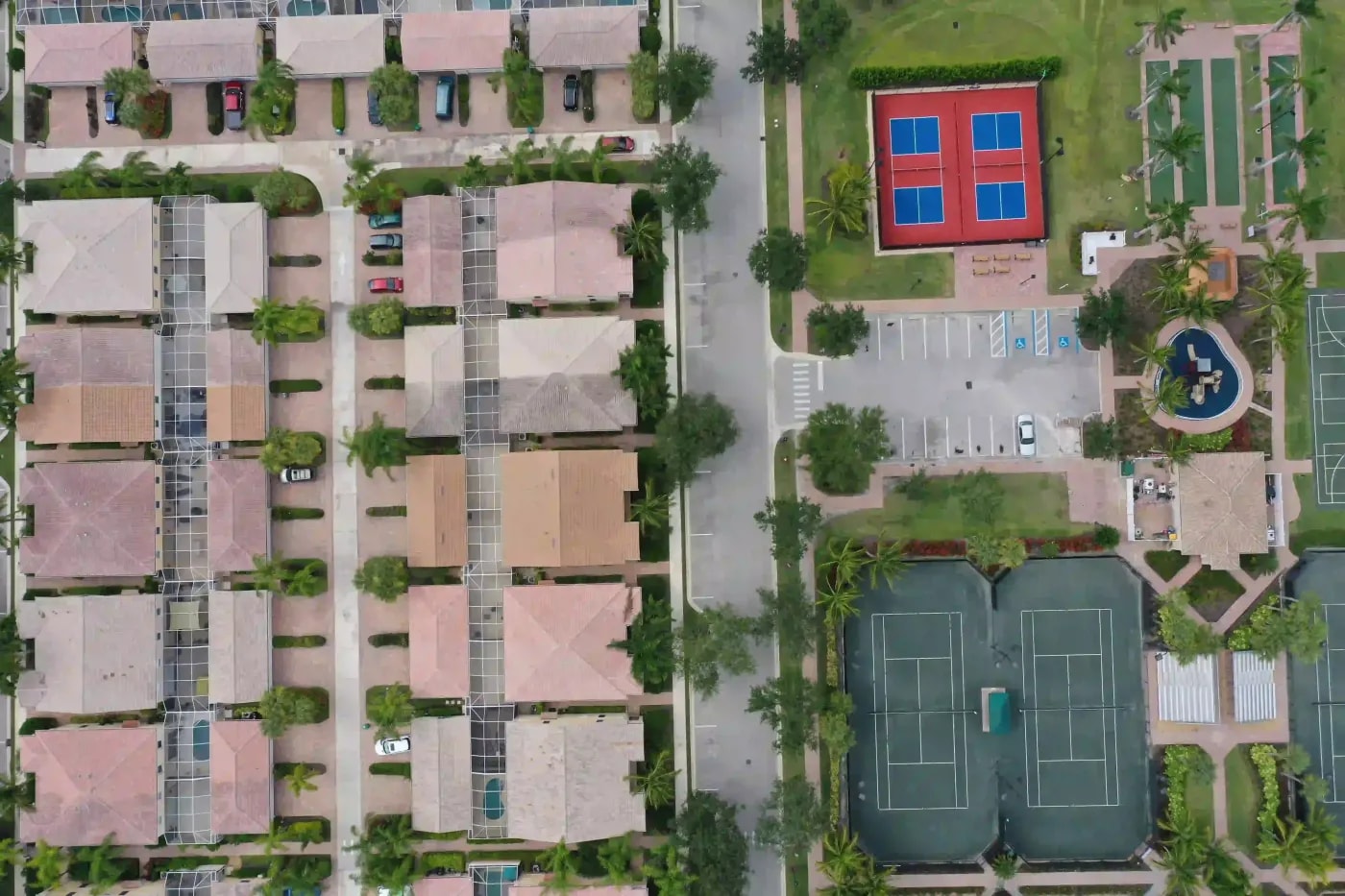 Overhead view of a planned residential neighborhood with tennis courts, palm trees, and organized lot structures