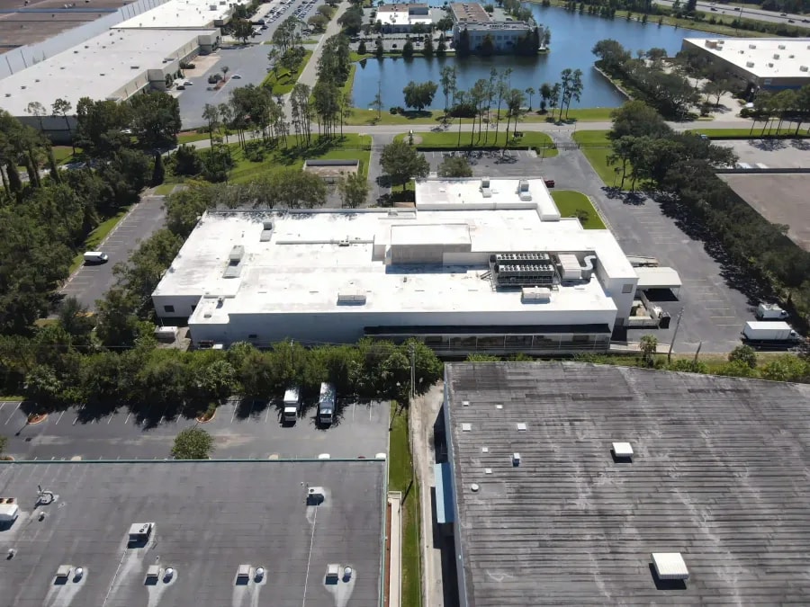 Aerial view of industrial park with surrounding water features and modern flat-roofed warehouses in a logistics area