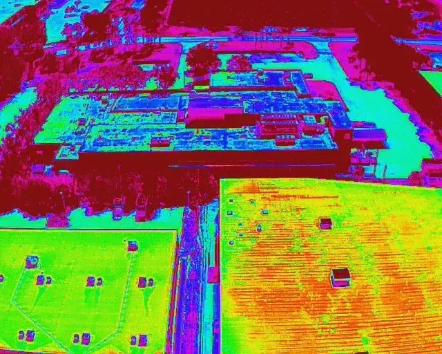 Thermal drone imaging showing heat distribution across flat industrial rooftops for energy efficiency and inspection