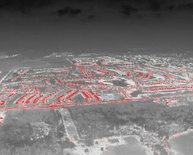 Infrared aerial image showing a planned residential neighborhood with red-highlighted heat zones and dense housing layout