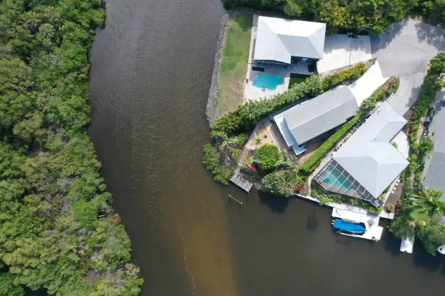 Overhead drone shot of waterfront homes with private docks and screened-in pools adjacent to a natural canal