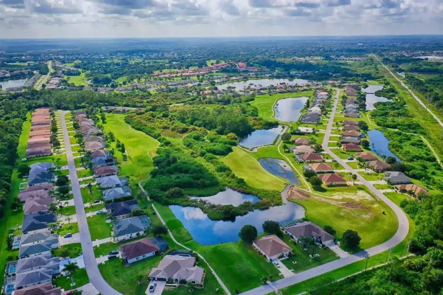 Drone view of suburban development featuring natural ponds, open green space, and symmetrical street layout