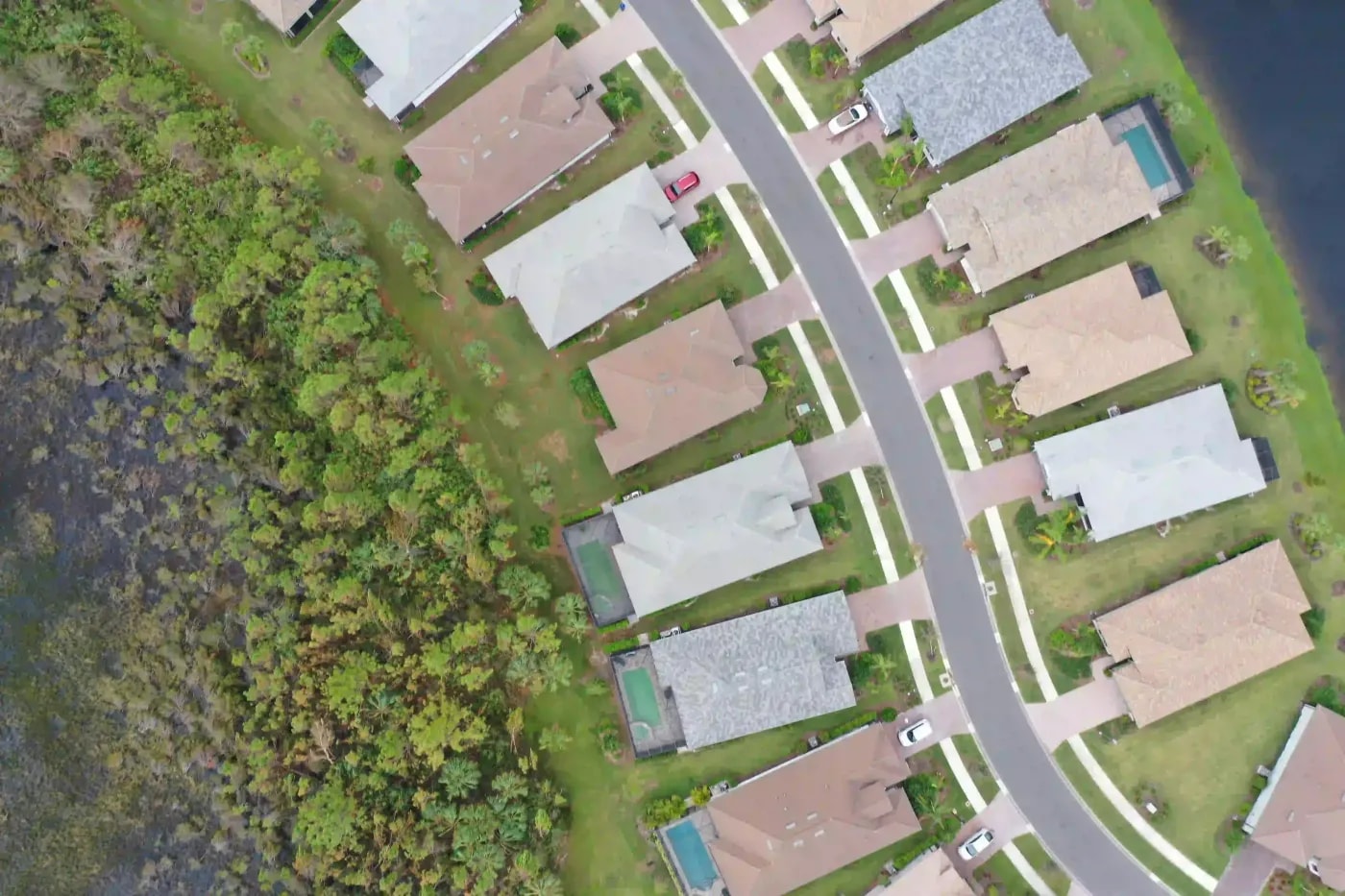 Top-down aerial image of suburban homes bordering a preserved wetland zone with defined backyards
