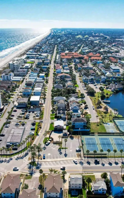 Aerial view of beachside neighborhoods with tennis courts, condos, and dense roadway access in a coastal corridor