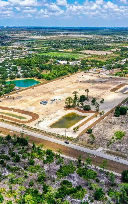 Drone capture of land grading in early development phase with retention ponds and surrounding suburban density