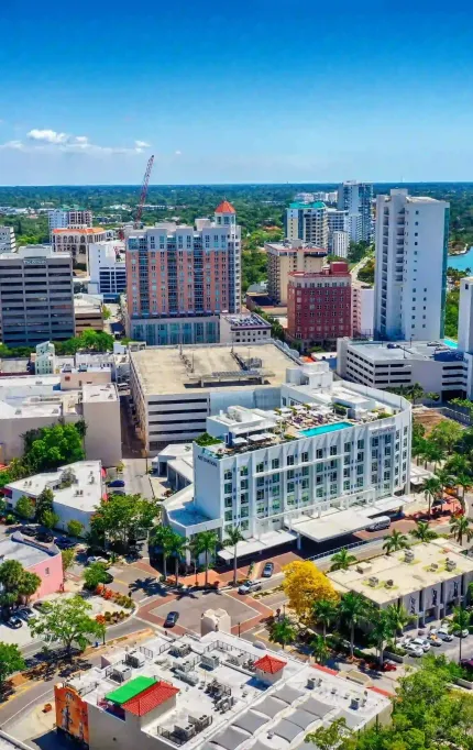 High-angle cityscape showcasing mid-rise and high-rise buildings near a bayfront with visible marina